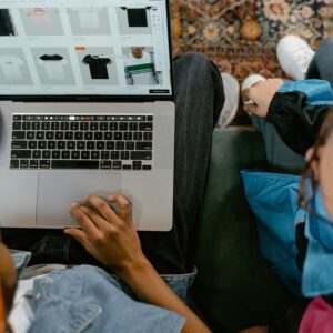 Two people browsing online clothing store on a laptop from above.
